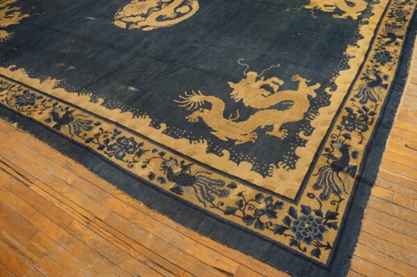 Navy blue and gold rug with stylized dragon patterns rests on rustic light brown hardwood flooring.