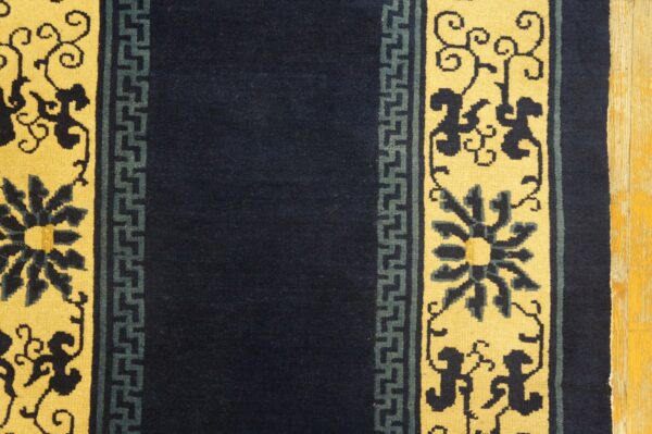 Navy blue runner rug with yellow borders featuring dark floral and teal geometric patterns on wood floor.