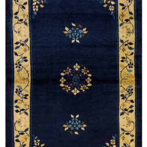 Dark blue rug with ochre floral borders and repeating blue and yellow stylized central medallions.