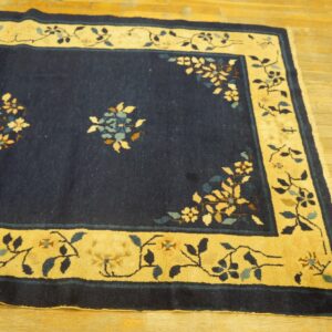 Navy blue rug with a yellow border and vine pattern, featuring subtle floral details on wood flooring.