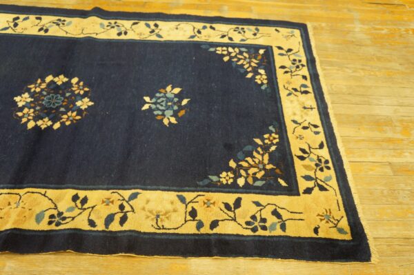 Navy blue rug with a yellow border and vine pattern, featuring subtle floral details on wood flooring.