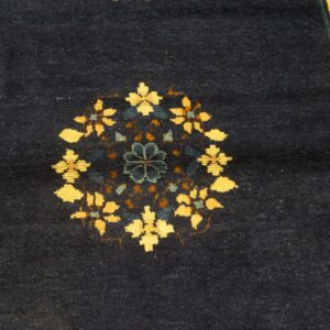 Navy blue rug with a central floral medallion in yellow and blue, next to a wide yellow border.