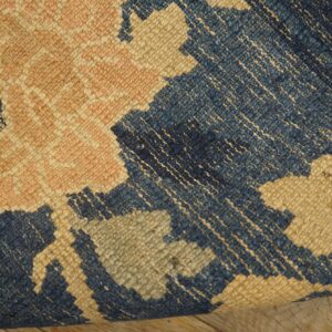 Textured blue, beige, and pink geometric rug detail resting on rustic wooden floorboards.