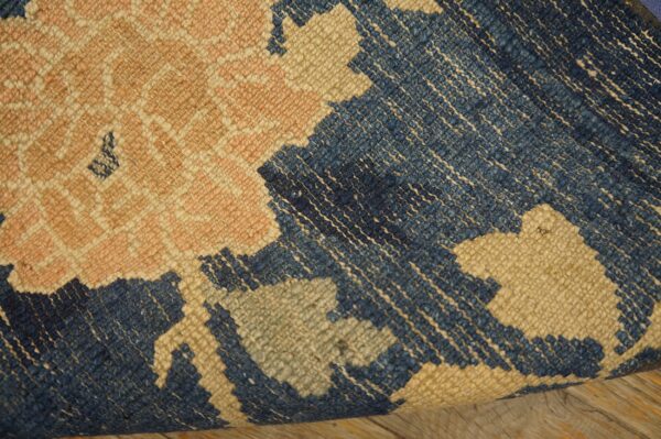 Textured blue, beige, and pink geometric rug detail resting on rustic wooden floorboards.