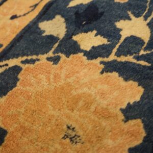 Close-up of a medium-pile rug featuring large peach and cream flowers contrasting with a dark blue background.