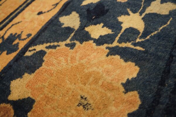 Close-up of a medium-pile rug featuring large peach and cream flowers contrasting with a dark blue background.