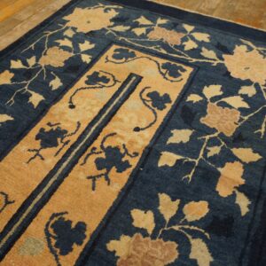 Navy blue rug with a gold medallion and stylized flowers on light wood planks.