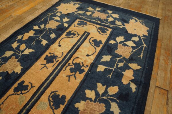 Navy blue rug with a gold medallion and stylized flowers on light wood planks.