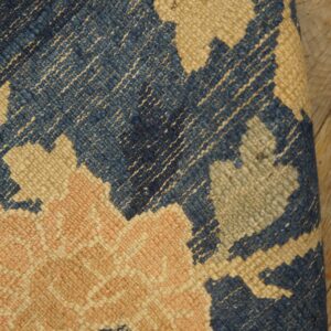 Rug detail shows low-pile blue, beige, pink, and gray floral patterns resting on a wood floor.