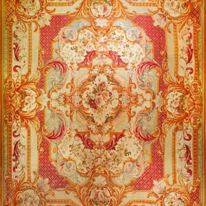 Symmetrical Baroque rug featuring large floral bouquets, heavy scrollwork, and rich coral and cream tones.