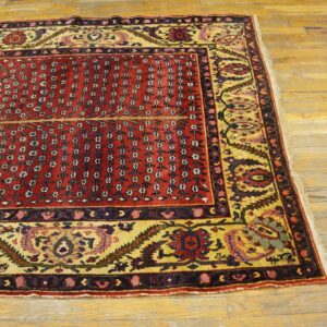 Red rug displaying vertical floral sprays and a wide yellow border on distressed wood floors.