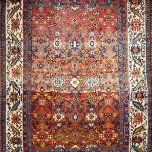 Red and navy traditional rug with intricate floral patterns and a wide ivory multi-color stylized border.