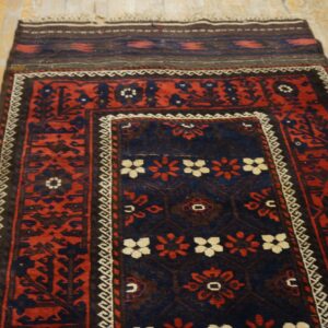 Red and dark blue traditional rug featuring floral and geometric medallions on light wood flooring.