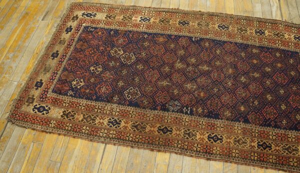 Geometric patterned runner rug in navy, tan, and red on distressed yellow-toned hardwood planks.
