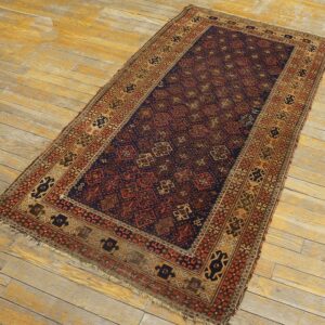 Navy blue and rust red low-pile geometric rug lying on weathered light brown wood flooring.