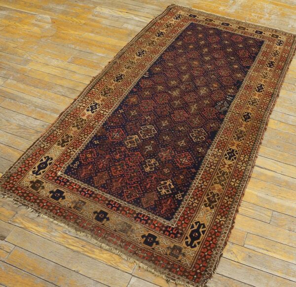 Navy blue and rust red low-pile geometric rug lying on weathered light brown wood flooring.