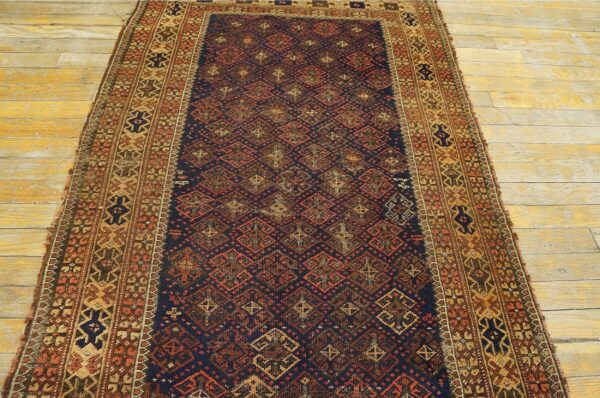 Low-pile navy runner rug with rust and tan geometric patterns displayed on light distressed wooden floors.