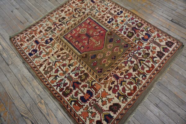 Geometric rug with a red medallion and multicolor tribal patterns displayed on distressed plank flooring.