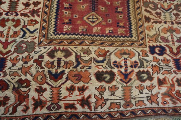 Detailed view of a geometric patterned rug featuring deep red, cream, rust orange, and navy blue colors.