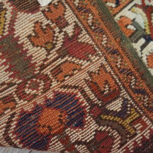 Detail of a patterned rug edge, showing the thick pile next to the flatwoven back on wood flooring.