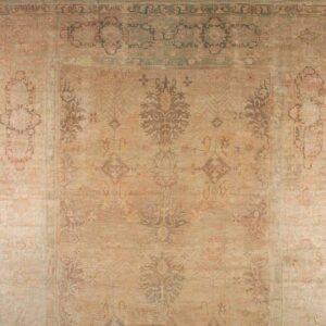 Close-up of a faded gold and olive rug with a large central medallion design.