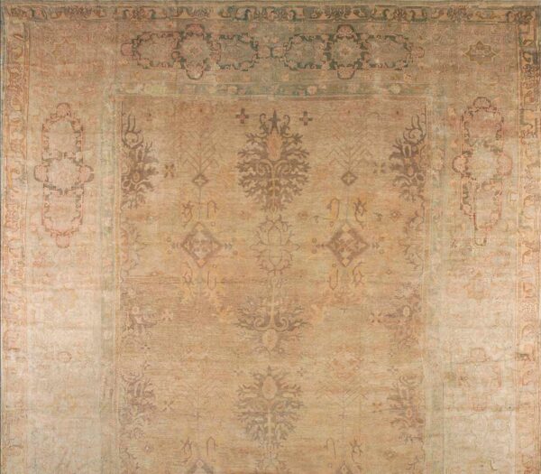 Antique oversized oushak turkish medallion knotted rug 1 Close-up of a faded gold and olive rug with a large central medallion design.