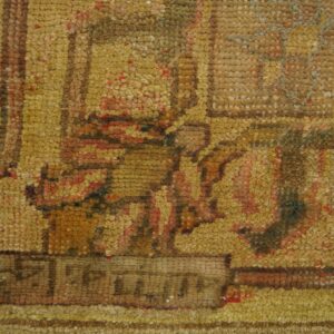 Detailed close-up of a textured rug with knots in golden yellow, brown, and muted red patterns.