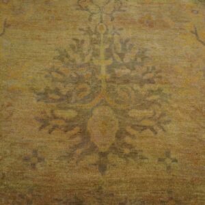 Textured low-pile rug detail showing a faded medallion in muted olive, ochre, and brown tones.