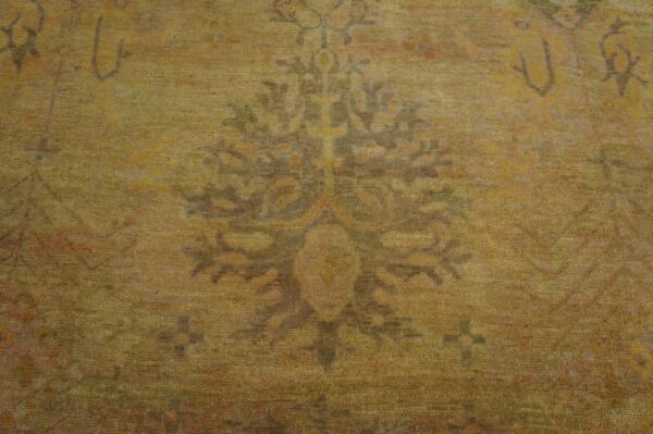 Antique oversized oushak turkish medallion knotted rug 8 Textured low-pile rug detail showing a faded medallion in muted olive, ochre, and brown tones.