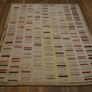 Textured cream rug featuring columns of short, colorful stripes resting on dark wood floors.