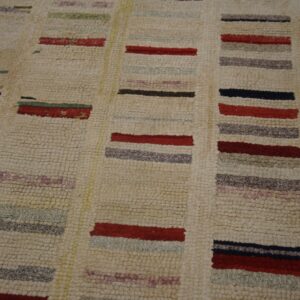 Beige loop-pile rug with columns of short, colorful stripes in red, maroon, black, and pale green.