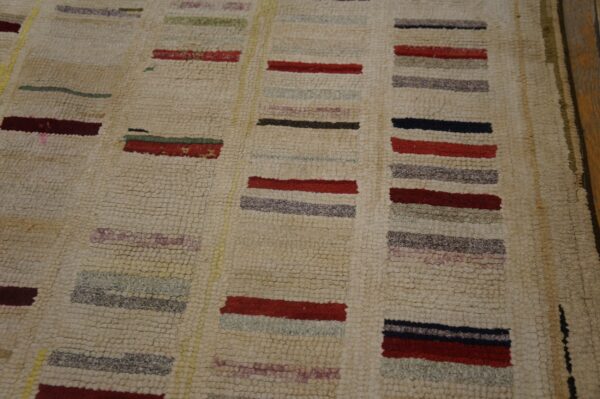 Beige loop-pile rug with columns of short, colorful stripes in red, maroon, black, and pale green.