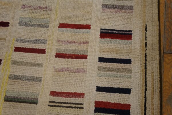 Nubbly cream rug featuring colorful horizontal blocks of red, navy, gray, and purple beside wooden planks.