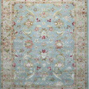 Light blue rug with an ornate floral pattern featuring a wide tan border and multicolored accents.