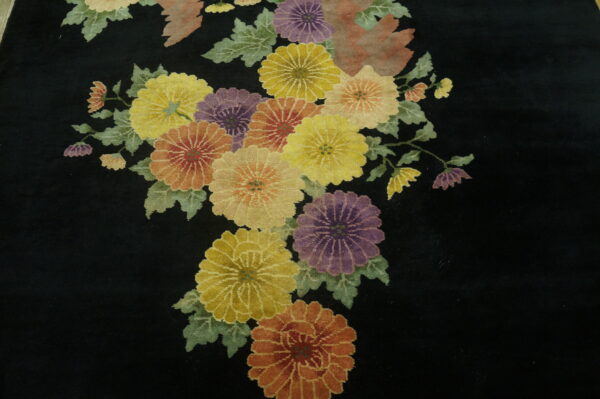 Low-pile rug detail showing multicolored floral sprays on a black ground with a soft pink zigzag stripe.