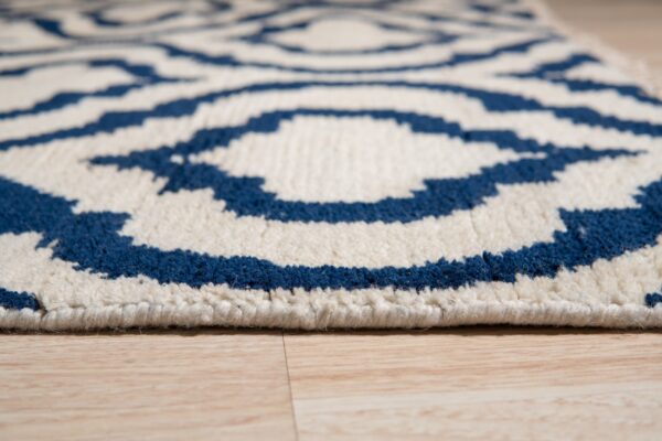 Blue and white plush rug with a geometric pattern sits close-up on light wood plank flooring.