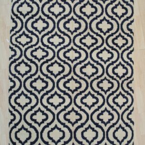 Navy and cream rug with an interlocking geometric pattern, laid flat on light wood planks.