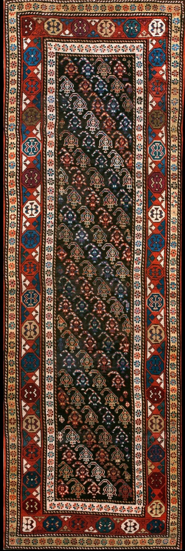 Dark geometric runner rug featuring a black center field with stylized patterns and wide borders in red, blue, and cream.