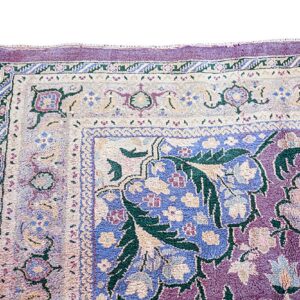 Ornate high-pile rug detail featuring floral and vine motifs in plum, light blue, cream, and deep green.