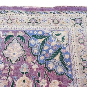 Ornate purple rug detail showing cream borders and dense floral motifs in blue and green.