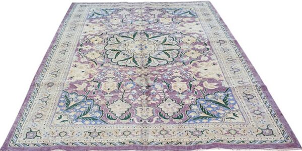 Ornate area rug with a center medallion and floral vines, colored in lavender, ivory, blue, and green.