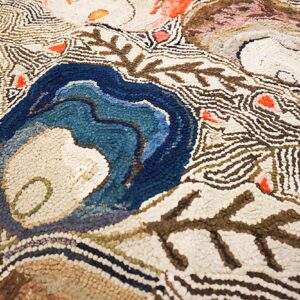 Textured rug detail with large blue, brown, and red organic shapes outlined by wavy cream and brown lines.