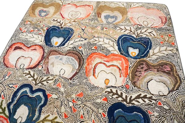 Textured rug featuring large abstract floral motifs in blue, coral, and brown, outlined by dense wavy linework.