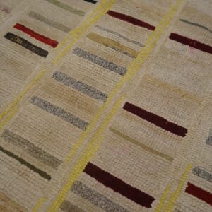 Textured cream rug features multicolored stripes (red, grey, olive) and diagonal bright yellow dividing lines.