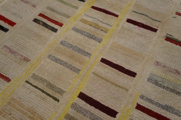 Textured cream rug features multicolored stripes (red, grey, olive) and diagonal bright yellow dividing lines.