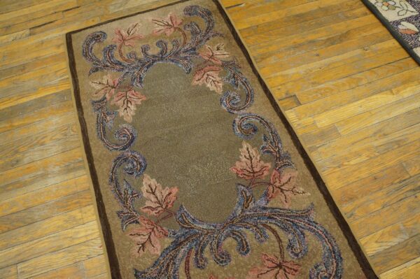 Taupe runner rug with pink leaves and blue scrolling vines rests on rustic yellow hardwood planks.