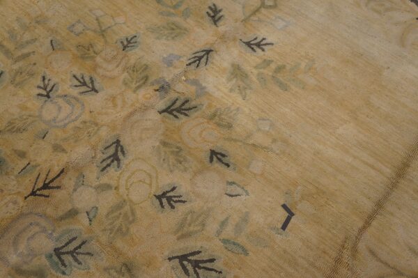 Textured beige rug featuring a mottled floral design of dark brown leaves and faint blue elements.