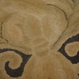 Textured rug detail featuring tan looped pile contrasting with dark brown scrolling leaf motifs.