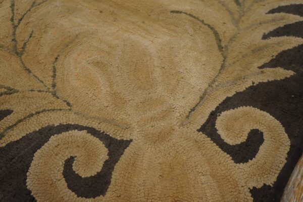 Textured rug detail featuring tan looped pile contrasting with dark brown scrolling leaf motifs.