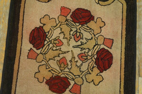 Close-up of a textured beige rug featuring a floral pattern of deep red roses and tan foliage with dark borders.